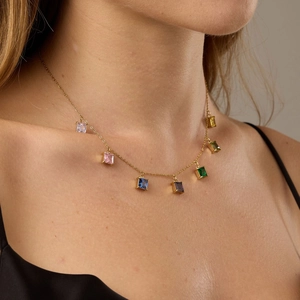 Dettaglio di un'elegante collana dorata con sette pendenti in zircone quadrato colorato
