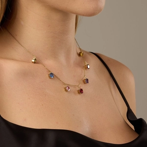 Gold necklace with multi-colored cubic zirconia pendants shown on model neckline