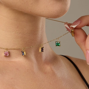 Elegante collana d'oro con cinque pietre di zircone quadrate colorate su una modella