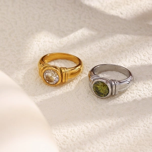 Macro shot of 18K gold and silver rings with round zircon and green gemstone insets