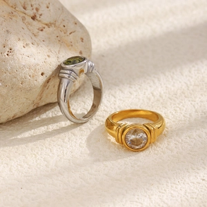 Detailed macro view of 18K gold and silver rings with round zircon stones on sandy texture