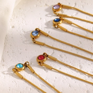 Detail von 18K vergoldeten Schlangenarmbändern mit bunten runden Zirkonia-Anhängern