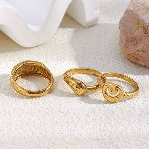 Detaillierte Ansicht von drei 18K vergoldeten Edelstahlringen mit Spiralmotiven auf Steinen