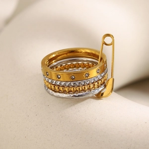 Macro view of four-layer mixed metal rings with safety pin charm and star engraving