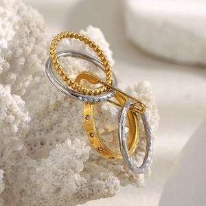Macro detail of 18K gold plated safety pin layered ring set with star engraving and crystals