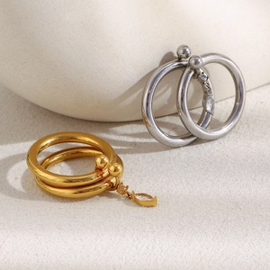 Detail of 18K gold and silver rings with marquise-cut zircon drops on stone surface