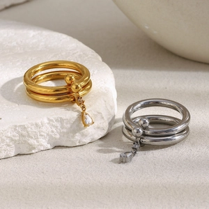 Detail of 18K gold and silver double-layered rings with teardrop cubic zirconia charms