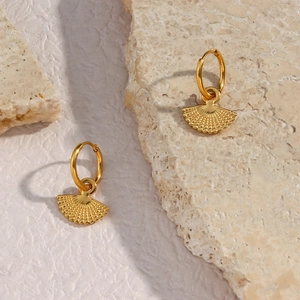 Detailed view of bohemian gold fan-shaped earrings on natural stone background