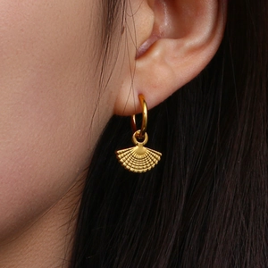 Bohemian fan-shaped golden earrings featuring radial bead detailing on a model