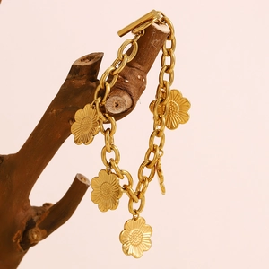 Détail de breloques tournesol en plaqué or 18K sur bracelet gourmette avec fermoir OT
