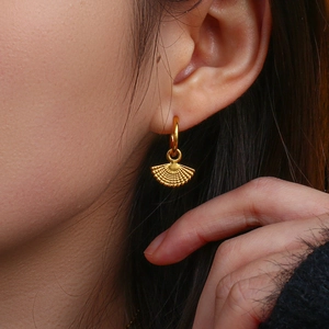 Detailed close-up of golden fan-shaped drop earrings with textured vintage finish
