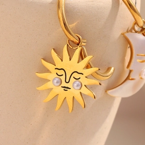 Macro shot of 18K gold plated sun and moon charms with pearl inlay and vintage carvings
