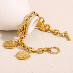 Détail des breloques marguerites en or 18 carats et du fermoir à bascule sur le bracelet