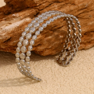 Close-up of three-row hammered silver discs on an open stainless steel cuff bracelet
