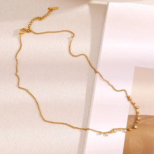 Détail d'une chaîne en acier doré 18K avec breloques en zircon rond et fermoir mousqueton