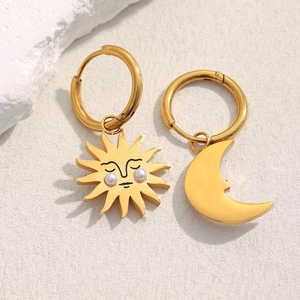 Detail of asymmetrical sun and moon hoop earrings in 18K gold plating with pearls