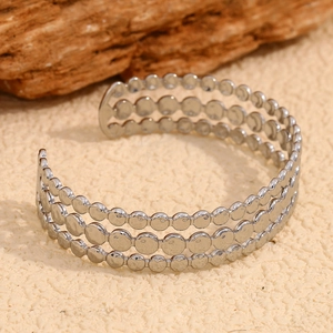 Detail view of silver triple-layer disc bangle showing smooth polished metallic texture