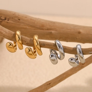 Minimalist double-layered twisted gold and silver ear cuffs on a natural wood branch