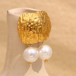 Détail de boucles d'oreilles martelées plaquées or 18K avec de grandes perles blanches