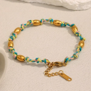 Macro détaillée de perles plaquées or 18K sur un bracelet en cordon tressé avec étiquette K18