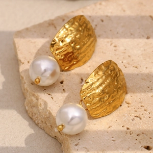 Détail montrant la texture martelée du métal doré 18K et la perle blanche ronde