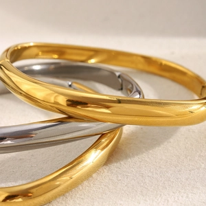 Détail de trois bracelets joncs empilables en acier inoxydable plaqué or 18 carats