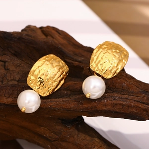 Détail de boucles d'oreilles martelées plaquées or 18 carats avec perles sur bois