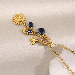 Primer plano detallado de la cadena de clips en oro de 18K con colgantes de sol y abeja