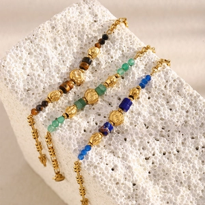 Detailed macro of vintage 18K gold plated beaded bracelets with natural stones on a stone base