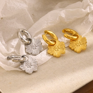 Detail of flower drop earrings in gold and silver finish with embossed petal textures
