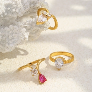 Dettaglio di tre anelli placcati in oro 18K con zirconi a goccia su una pietra di corallo