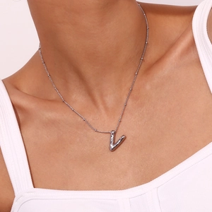 Detail van een zilveren V-vormige hanger aan een fijne kralenketting voor vrouwen