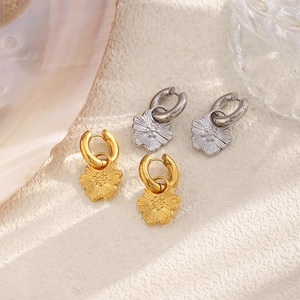 Detailed view of floral pendant hoop earrings in gold and silver finishes
