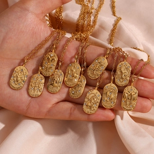Macro detail of gold oval zodiac pendant necklaces with zircon inlay on silk background