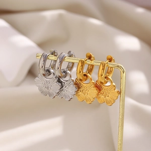 Elegant 18K gold and silver petal pendant earrings displayed on a luxury metal stand