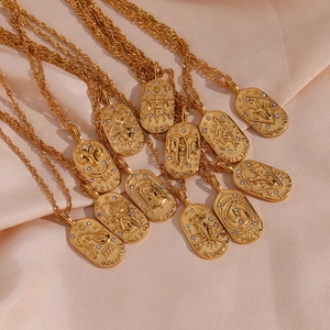 Detail of twelve golden oval zodiac necklaces with zircons on silk background