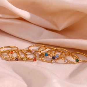 Detailed macro view of colorful 18K gold birthstone rings on soft silk fabric