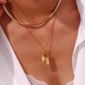 Détail d'un pendentif Cancer doré sur chaîne fine superposé avec un collier de tennis