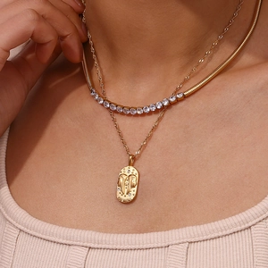 Close-up of gold layered Gemini pendant necklace with snake chain and zircon inlay
