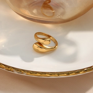 Macro-opname van verstelbare gouden druppelring op wit porselein met zijden stof