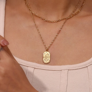 Detail of layered gold Sagittarius pendant necklace with cubic zirconia on a model