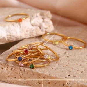 Detailed stack of slim 18K gold plated rings featuring colorful round gemstones on stone