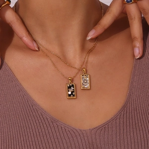 Close-up of gold tarot card pendants featuring The World and The Wheel of Fortune