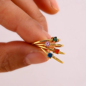 Macro detail of four minimalist 18K gold plated rings with round colorful birthstones