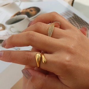 Detail van een gouden druppelring gecombineerd met een pavé-gezette ring met zirkoon