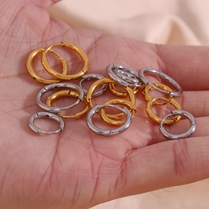 Close-up of gold and silver minimalist stainless steel hoop earrings held in hand