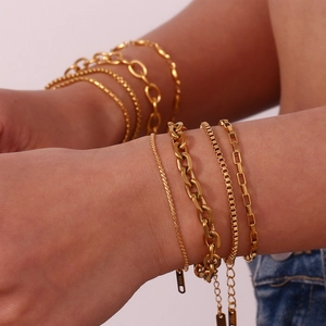 Detail of layered 18K gold plated stainless steel bracelets with lobster clasp and tag