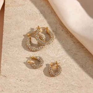 Dettaglio di orecchini a cerchio a U placcati oro 18K con zirconi su marmo