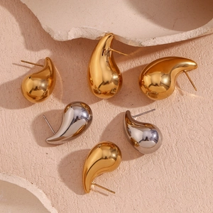 Boucles d'oreilles gouttes creuses en or 18 carats et argent sur fond de pierre texturé