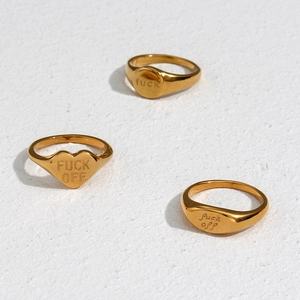 Trois bagues chevalières dorées aux formes cœur et rondes sur surface texturée